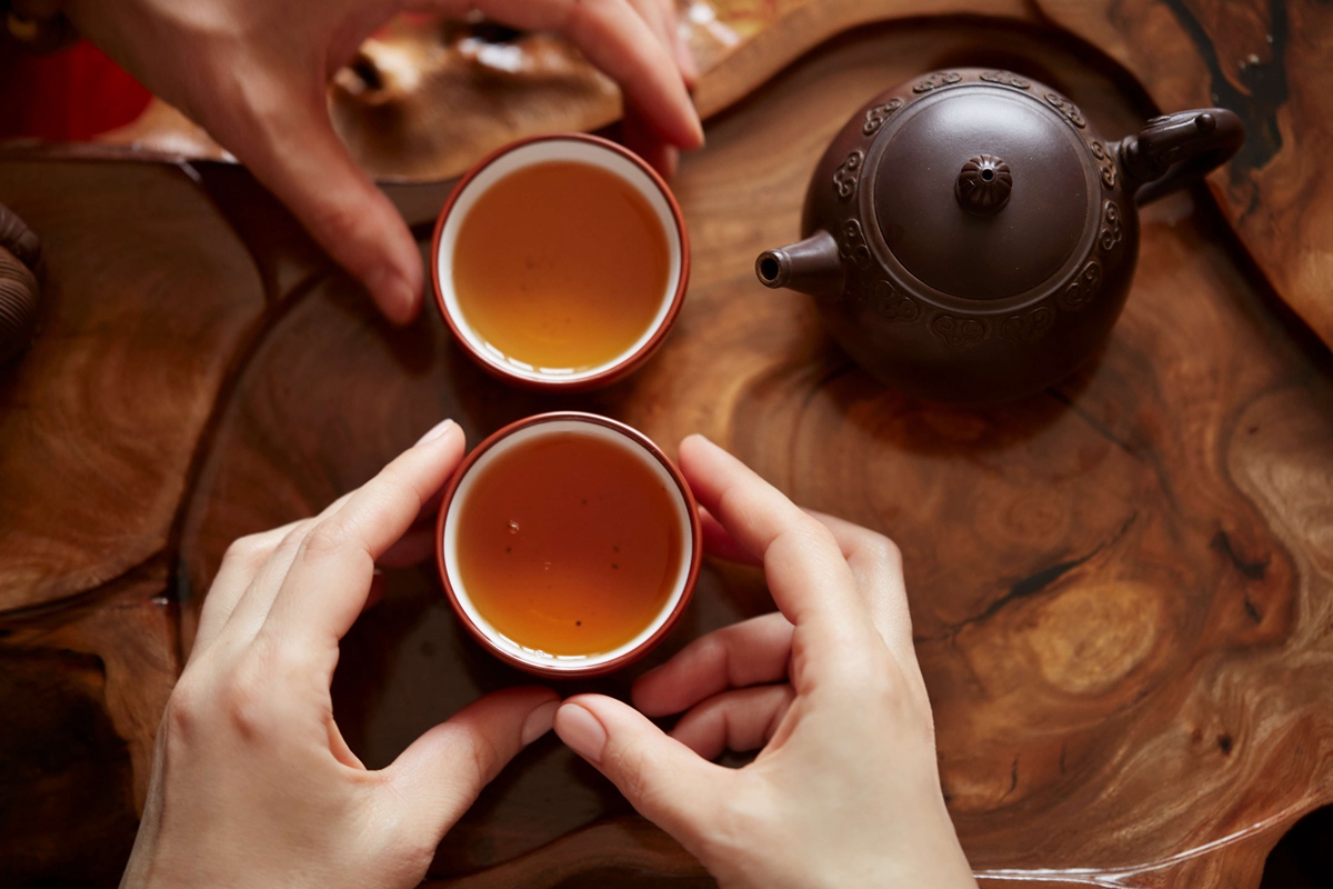 頂視圖茶具茶道背景的木桌。女人和男人捧著一杯茶.jpg